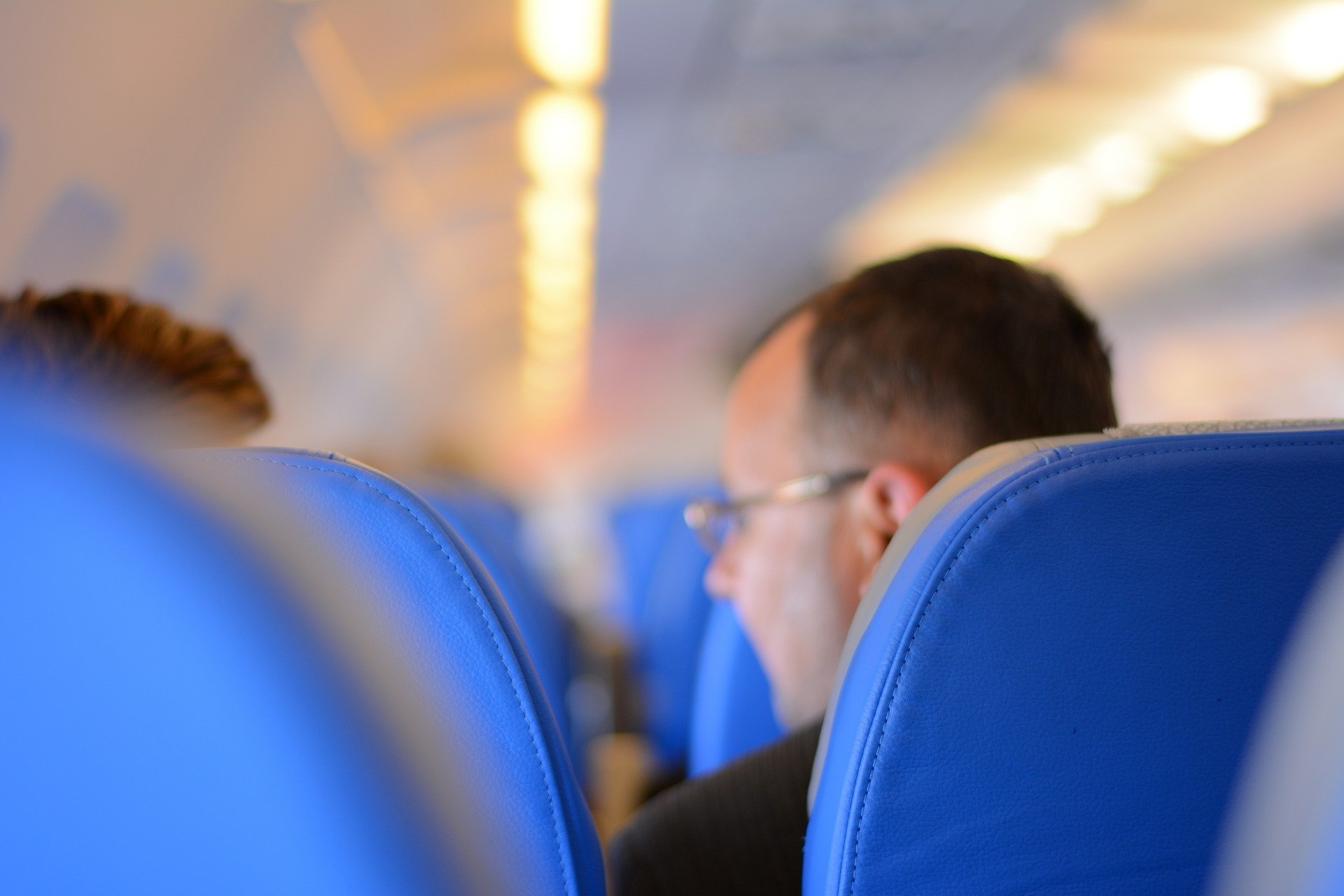 люди, напхані в економ-класі в літаку, сині сидіння